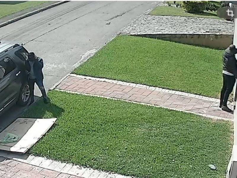 Captura de un video donde se observan a dos hombres haciéndose pasar como repartidores de encomiendas.