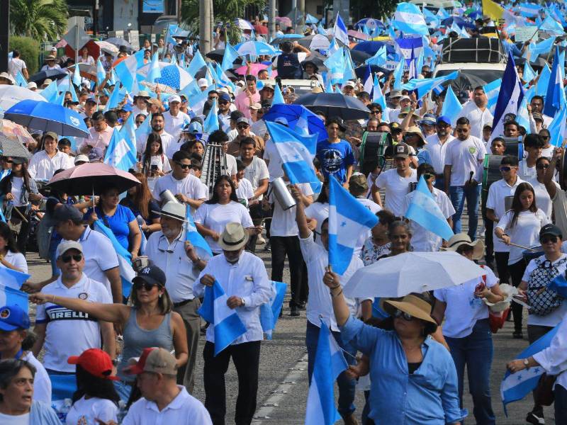 Personas sostienen banderas de Honduras durante la marcha por la paz en San Pedro Sula.