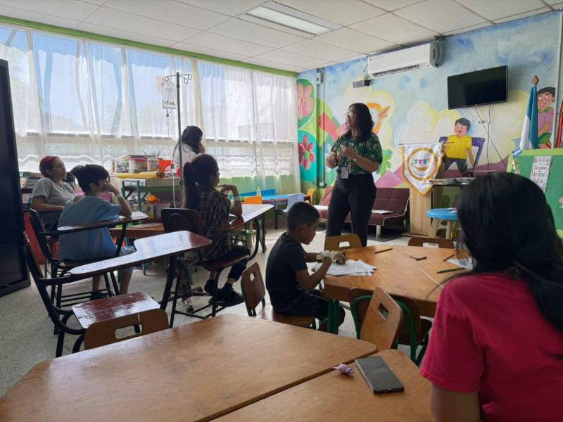 Un grupo de estudiantes y sus madres escuchan con atención las indicaciones de la profesora Natalia Barahona en la escuela del Mario Rivas.