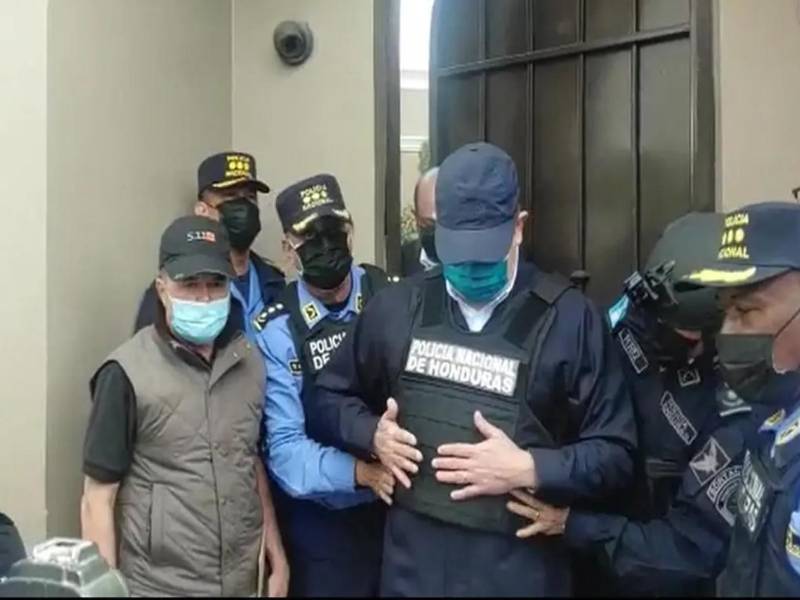 JOH salió de su residencia e inmediatamente policías le colocaron un chaleco antibalas y lo esposaron de pies y manos para trasladarlo a una unidad policial.