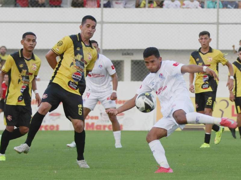 José Mario Pinto disparando de zurda ante Oliver Morazán que intenta bloquear el balón.