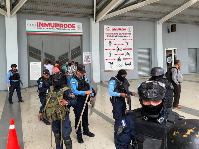 Agentes de la Policía Nacional resgardan el palacio de los deportes, mientras medios de comunicación dialogan con dirigentes de transporte a través de los portones que la Policía Municipal mantuvo cerrados.