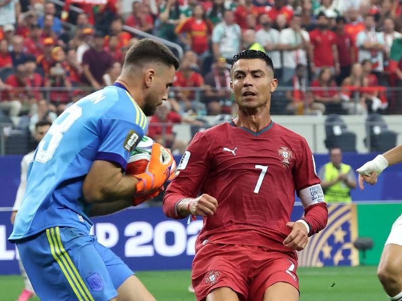 El portero Unai Simón de España se queda con el balón ante el acecho de Cristiano Ronaldo.