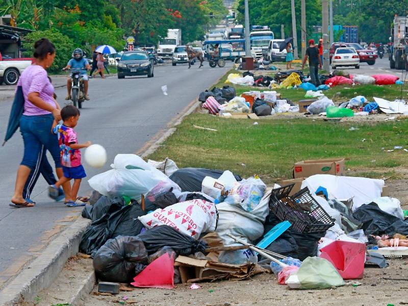 Personas transitan por la 33 calle, donde pobladores de colonias aledañas han sacado su basura a la mediana.