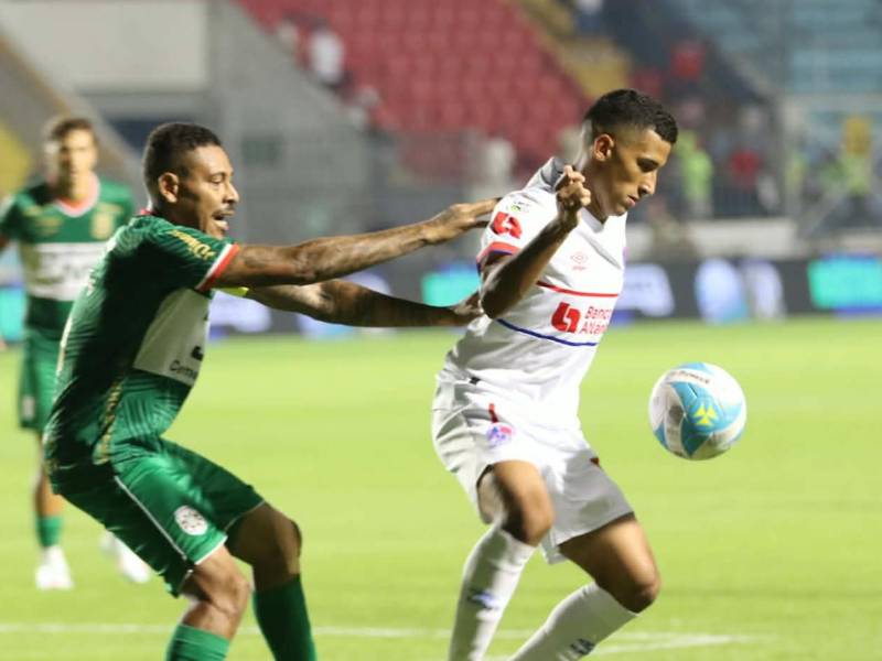 José Mario Pinto de Olimpia conduce la pelota ante la marca de Henry Figueroa, defensor del Marathón.