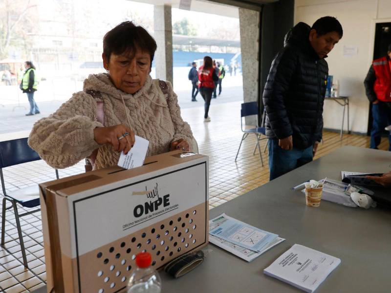 Una mujer deposita su voto en una urna este domingo, durante la segunda vuelta de las elecciones presidenciales en Perú, en Santiago.