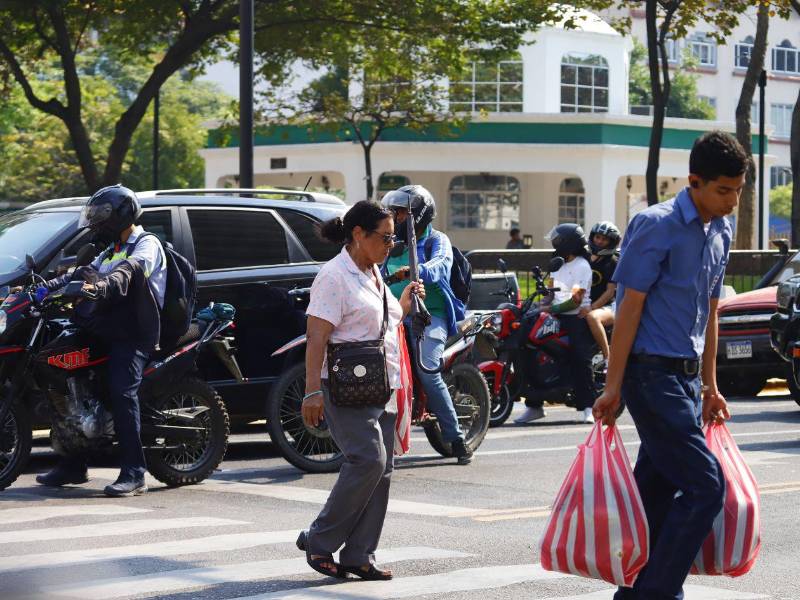 Pobladores circulan por la primera calle de San Pedro Sula en medio de intenso calor.