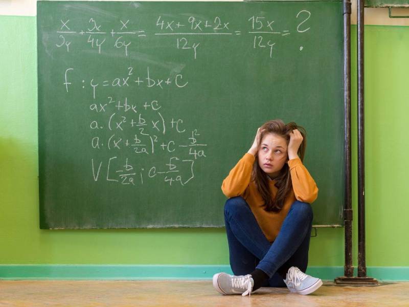 Una joven se bloquea frente a un ejercicio de matemáticas en una fotografía de referencia.