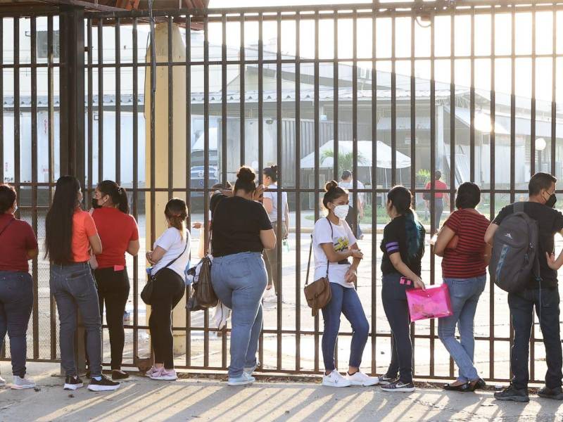 Un grupo de personas buscan empleo en San Pedro Sula con su hoja de vida en mano.