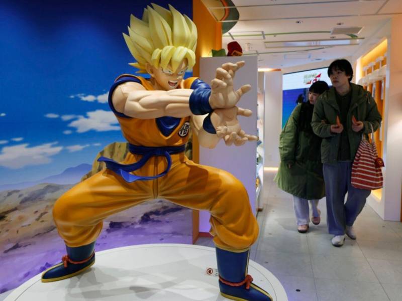 Visitantes caminan junto a un personaje de Dragon Ball exhibido en una tienda de Tokio, Japón.