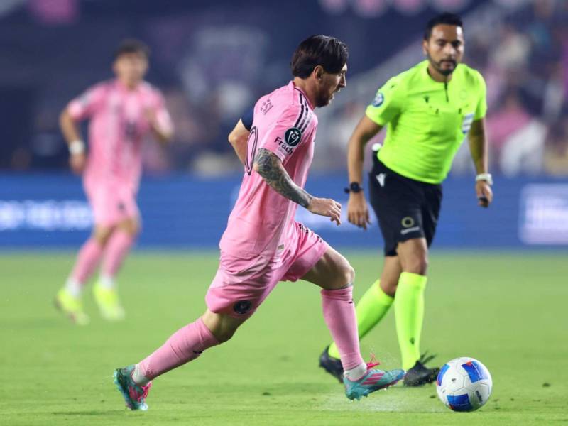 Messi conduce el balón y en el fondo lo observa el árbitro hondureño Said Martínez.