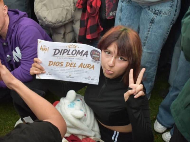 Una joven participante posa con su diploma durante una batalla de aura, una competencia que reúne a jóvenes en torno a esta tendencia viral.