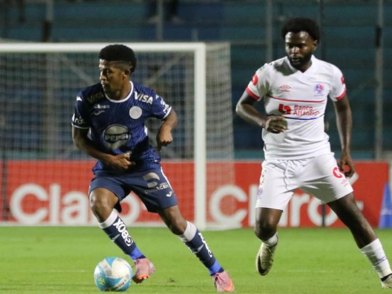 Jorge Serrano del Motagua conduce el balón ante la marca de Elison Rivas, lateral de Olimpia.