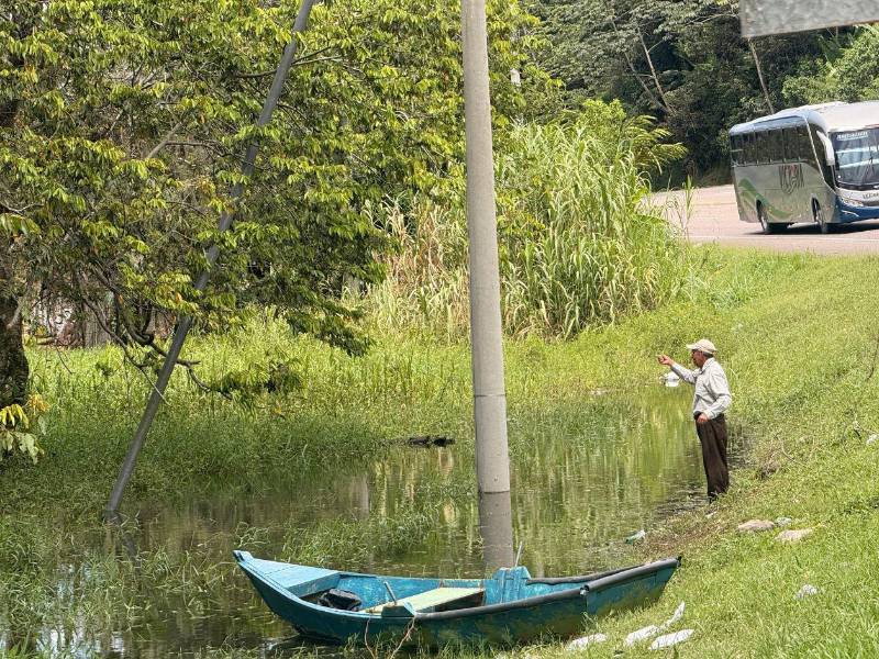 Mientras algunas familias rescatan sus pertenencias de las viviendas inundadas, otros aprovechan la crecida del lago para pescar desde las orillas de la carretera.