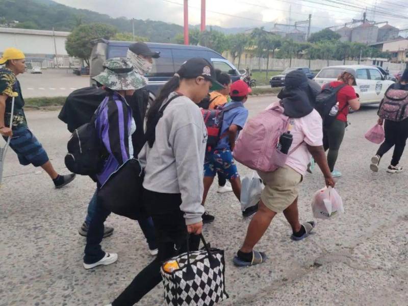 Migrantes hondureños avanzan con sus pertenencias por las calles de San Pedro Sula como parte de la nueva caravana que se dirige hacia Estados Unidos.