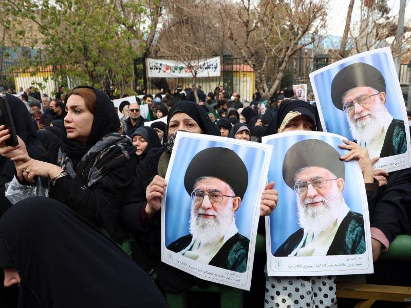 Un grupo de manifestantes prorégimen en Irán muestra unas fotos del líder supremo, el ayatolá Alí Jamenei, durante el funeral celebrado por los policías muertos durante las manifestaciones de protesta contra el régimen.