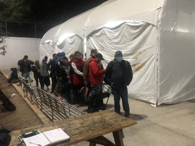 Un grupo de migrantes esperan para entrar a un albergue en Ciudad Juárez.