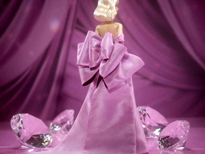 Una imagen de la parte trasera de la muneca, que lleva un vestido rosa con un enorme moño en la espalda.