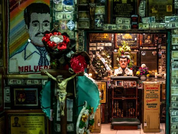 Ofrendas de flores, velas, fotos y billetes de dólar en un santuario dedicado a Jesús Malverde, un narcosanto, en Culiacán, México, el 25 de noviembre de 2024.