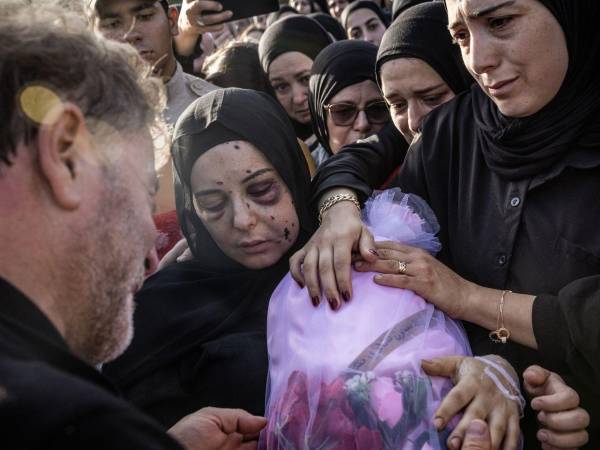 Amani Bazzi sostiene a su hija, envuelta, tras su muerte en un ataque con drones israelíes en el Líbano.