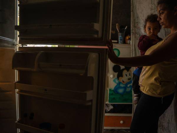 Una mujer muestra su refrigeradora casi vacía en Los Teques, Venezuela.