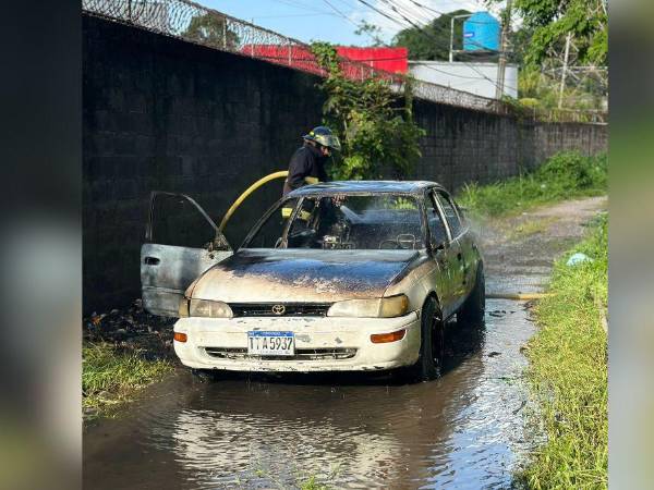 Bombero apaga el fuego provocado en una unidad de taxi en La Ceiba, Atlántida, Honduras.