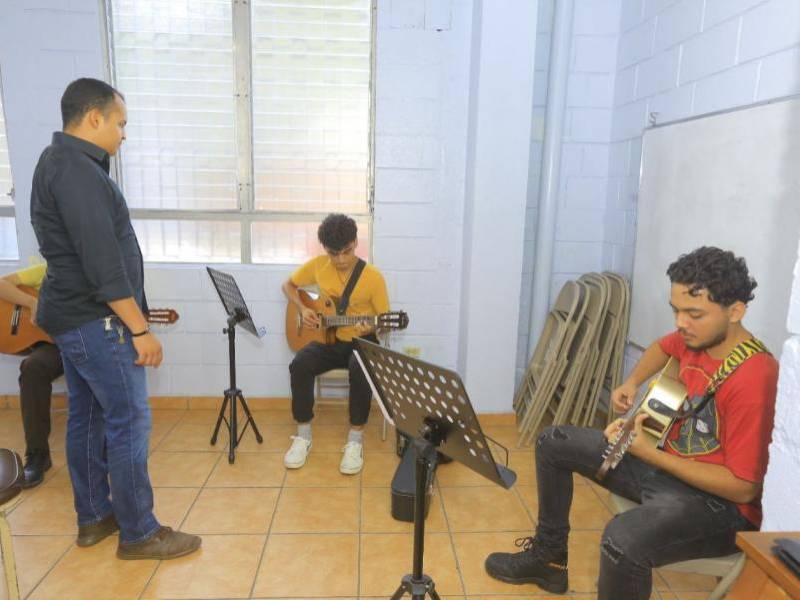 Alumnos practican guitarra durante una clase musical.