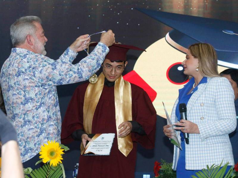 El alcalde Roberto Contreras y la máster Emma Mejía de Valladares entregan reconocimientos a Marlon Enamorado por su excelencia académica.