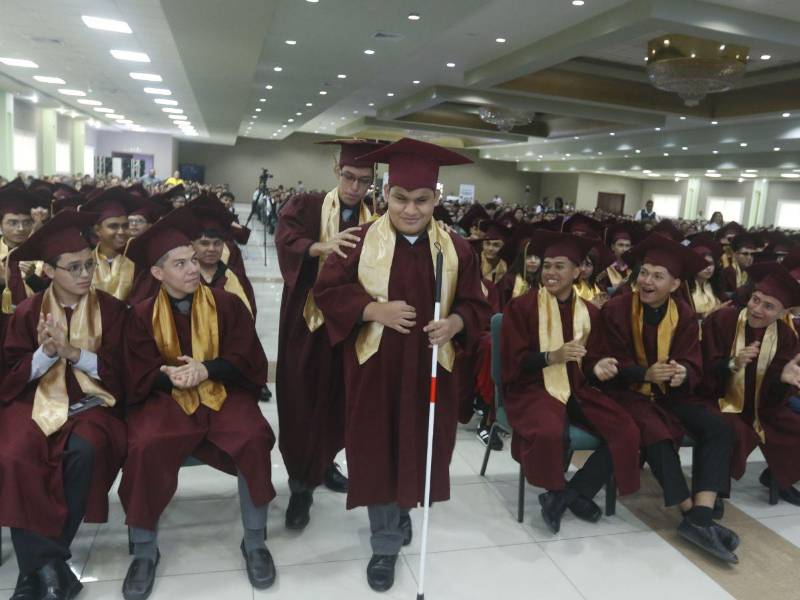 Un compañero acompaña a Marcelo al estrado para recibir su reconocimiento.