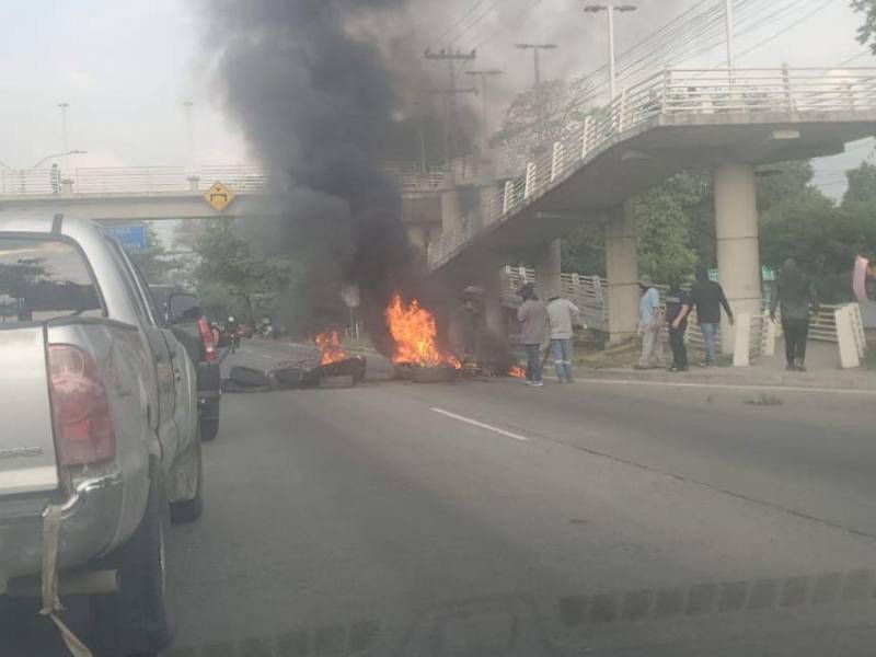 Con llantas quemadas y pancartas, exempleados del PNRP protestan en San Pedro Sula.