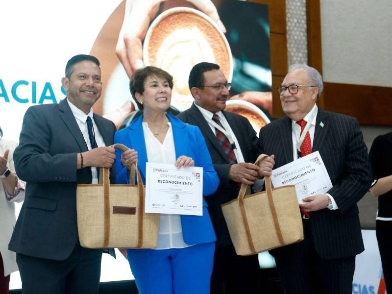 El gerente general del Ihcafé, Adilson Avila y el presidente del Ihcafé, Pedro Mendoza, entregan reconocimiento a la directora de la OIC, Vanusia Nogueira y el embajador de Honduras en Reino Unido, Iván Romero Martínez.