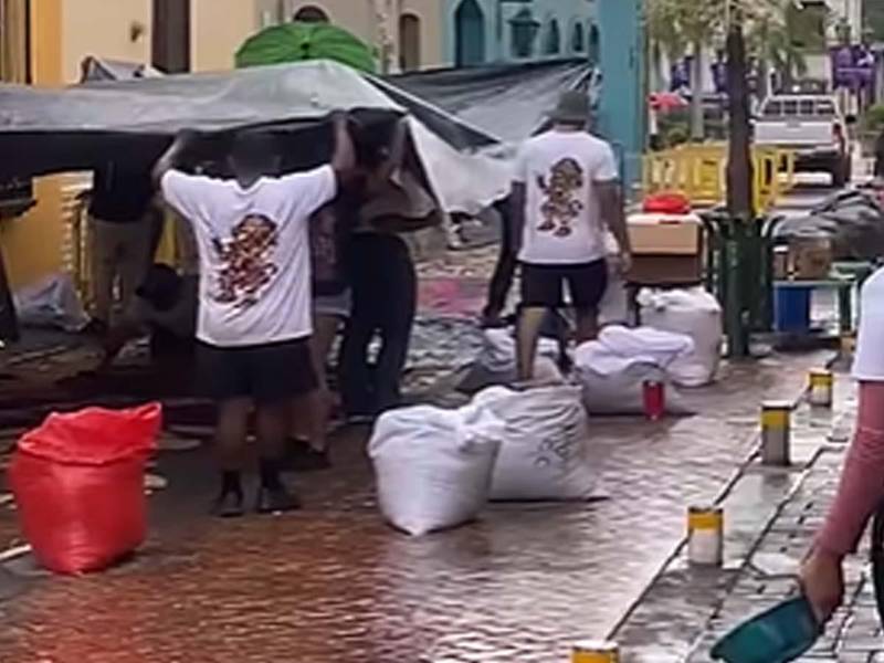 Feligreses de Comayagua luchan contra la lluvia para proteger las alfombras de aserrín.