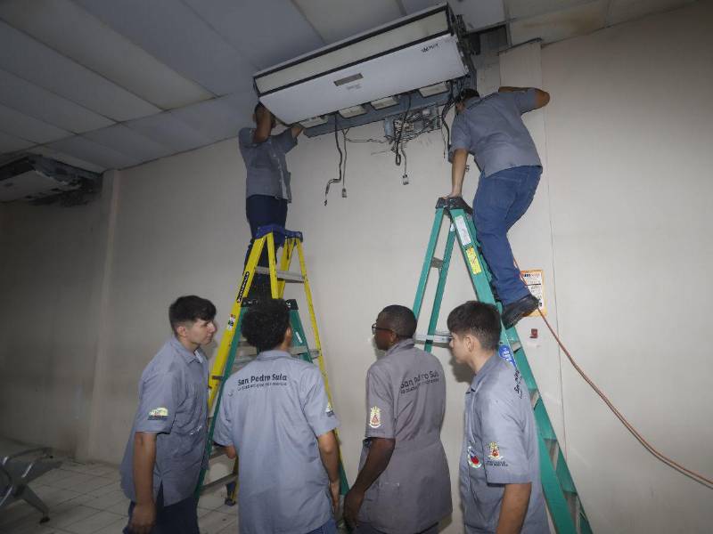 estudiantes del Centro de Capacitación Técnica Honduras Corea reparan aire acondicionado de la farmacia.