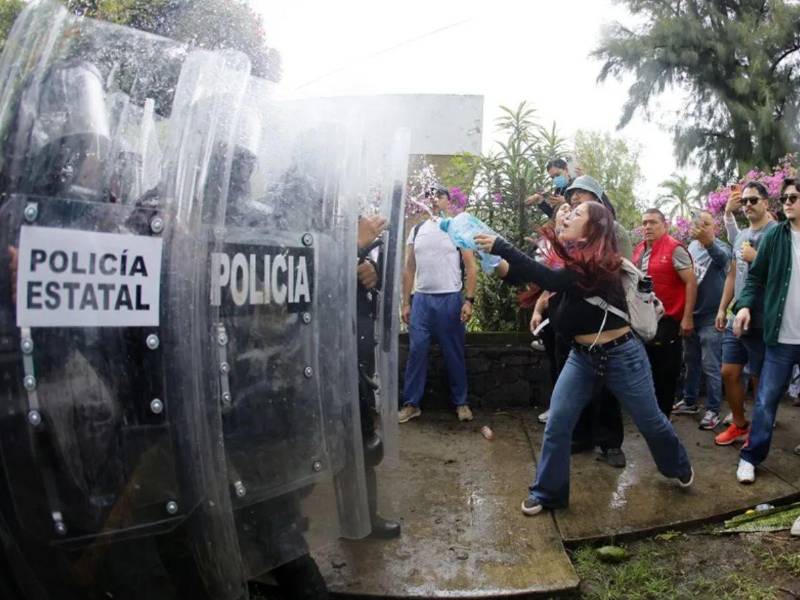 Personas se enfrentan con integrantes de la policía antimotines este domingo en Guadalajara.
