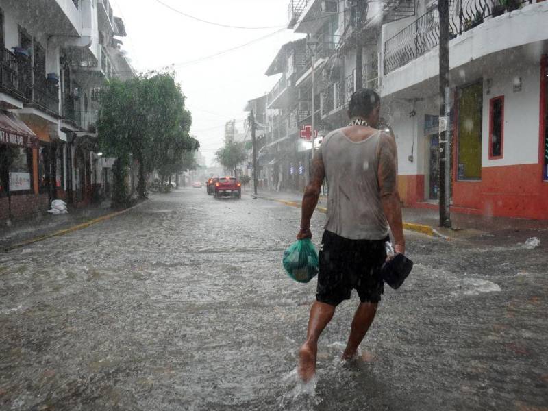Un hombre camina por una calle inundada por lluvias provocadas por Simón este martes, mientras la tormenta tropical Trudy se formaba en el Pacífico mexicano a partir de la depresión tropical Veintiuno-E, en Puerto Vallarta (México).