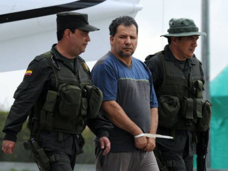 Daniel Rendon Herrera (C), a.k.a. 'Don Mario', is escorted by police officers on April 15, 2009 in Bogota, Colombia. Rendon Herrera, Colombia's biggest drug kingpin for whom the government had offered a 2.1-million-dollar bounty, was arrested by a special unit of 315 police in Antioquia Department. TOPSHOTS/AFP PHOTO/Rodrigo Arangua