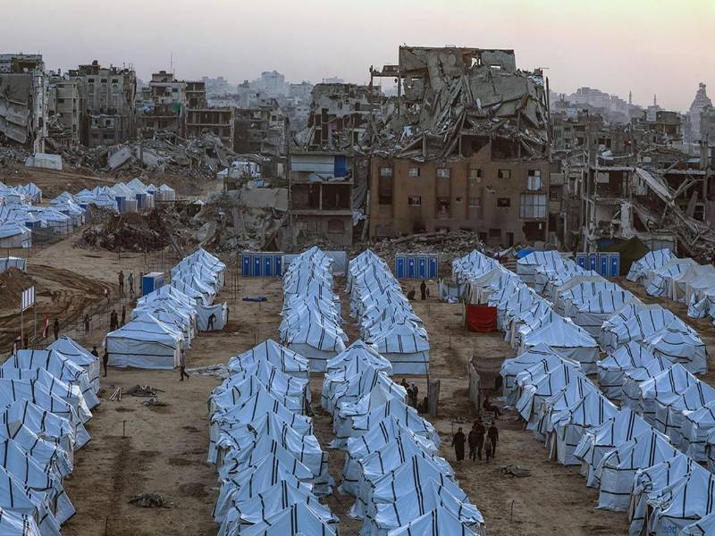 Palestinos desplazados caminan entre refugios improvisados erectos junto a los restos de edificios destruidos en la ciudad de Gaza Norte, Franja de Gaza, 18 de noviembre de 2025, en medio de un alto el fuego entre Israel y Hamás. EFE