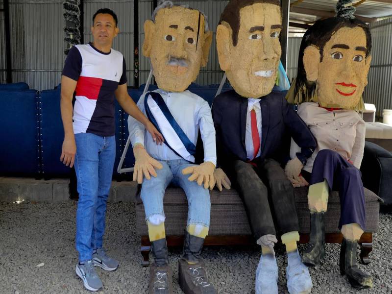 Luis Lagos, en su taller de tapicería, junto a las figuras del presidente electo de Honduras, Nasry 'Tito' Asfura, y de los candidatos presidenciales Salvador Nasralla y Rixi Moncada, representadas en monigotes elaborados por artesanos este martes, en Tegucigalpa (Honduras).