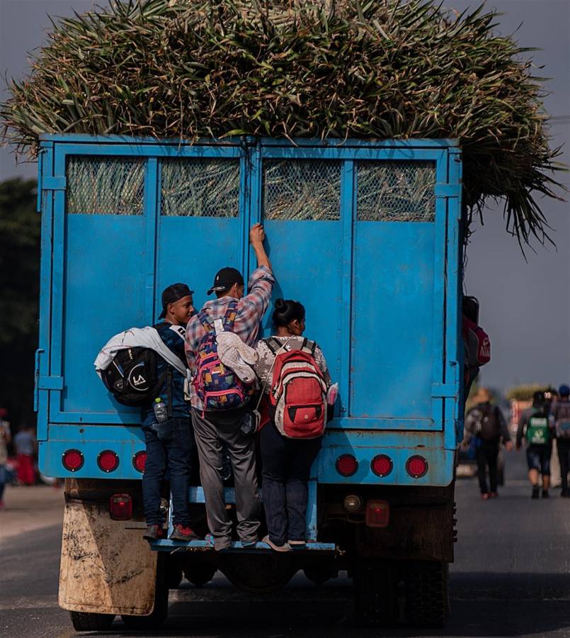 Migrantes se aferran a las puertas de un camión para avanzar en su recorrido hacia Ciudad de México.