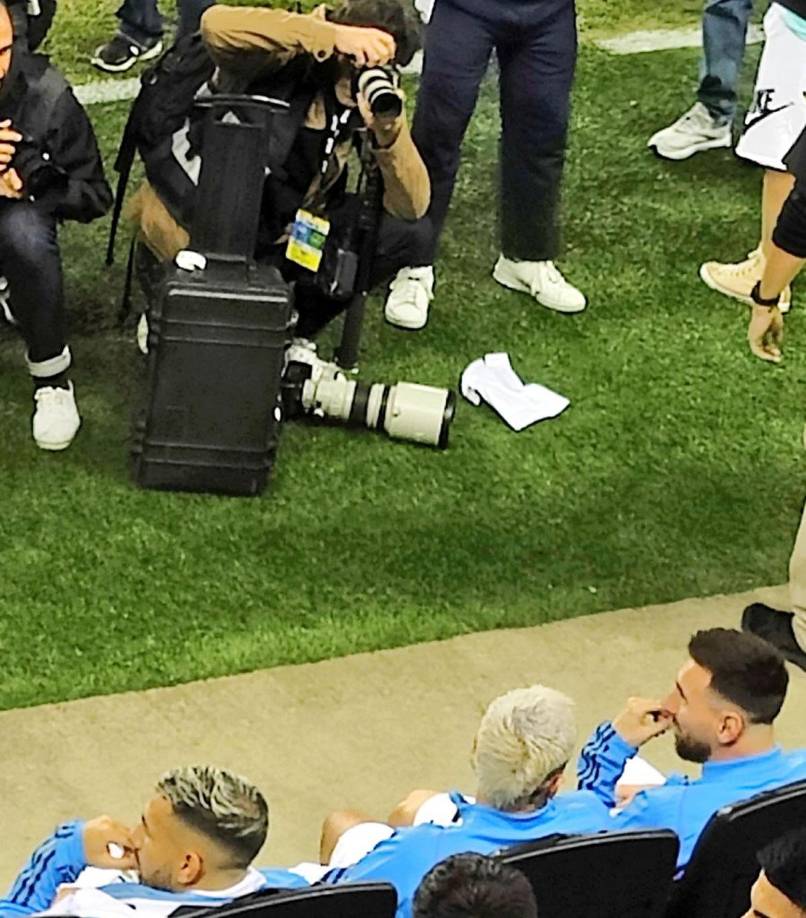 Messi, sonriendo en el banco de suplentes y los fotógrafos atentos.