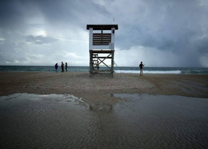 WRIGHTVILLE BEACH, NC- SEPTEMBER 11: People stand near a lifeguard stand as Hurricane Florence approaches, on September 11, 2018 in Wrightsville Beach, United States. Hurricane Florence is expected on Friday possibly as a category 4 storm along the Virginia, North Carolina and South Carolina coastline. Mark Wilson/Getty Images/AFP