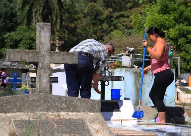 Una pareja limpia la cruz de una de las tumbas ubicadas en el cementerio La Puerta de San Pedro Sula con motivo del Día de los Muertos.