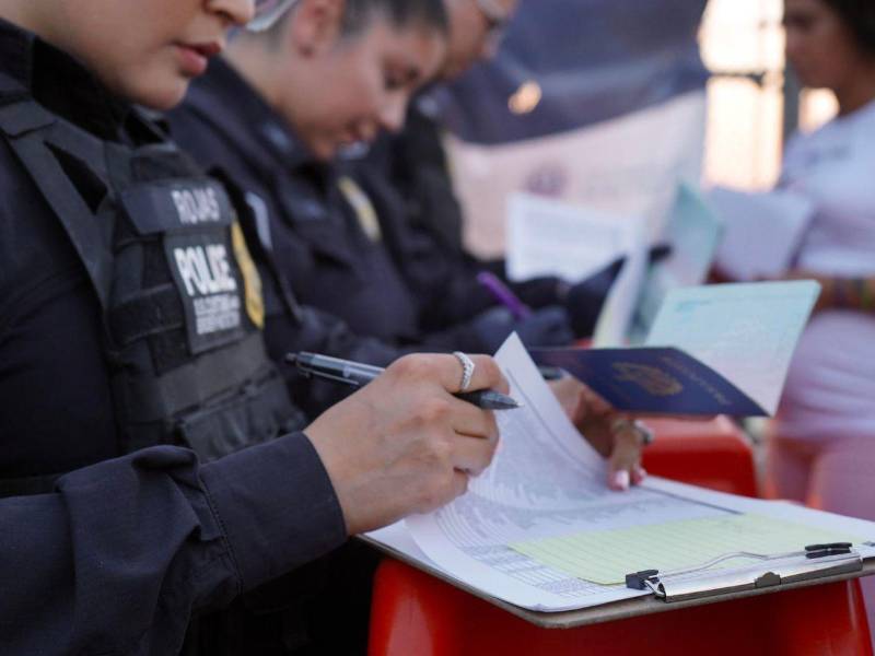 Una agente de la Oficina de Aduanas y Protección Fronteriza de Estados Unidos (CBP) apunta los nombres de inmigrantes que van a entregar su aplicación de entrada a Estados Unidos en la frontera de El Paso,Texas.