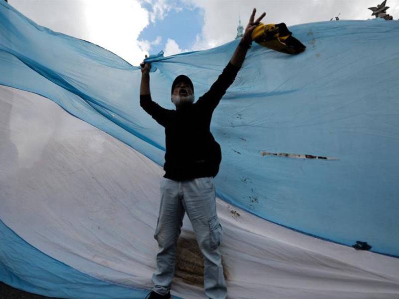 Un manifestante grita consignas agitando una bandera de Argentina en una protesta de los jubilados.