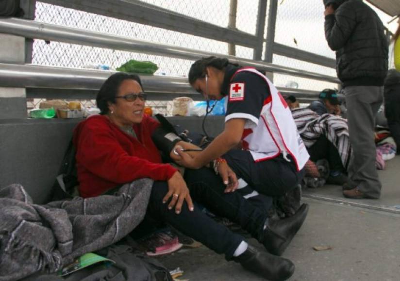 Miembros de la Cruz Roja mexicana atienden a los migrantes que, desafiando las bajas temperaturas, duermen a la intemperie por varios días esperando ser atendidos por las autoridades migratorias estadounidenses.