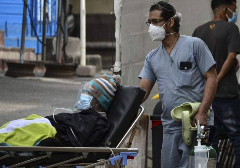 Un médico ayuda a un hombre infectado con COVID-19 en un hospital de campaña establecido en el patio de la Escuela Hospotal en Tegucigalpa. AFP