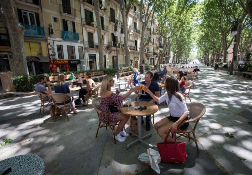 People share a toast at a terrace bar in Palma de Mallorca on May 11, 2020, as Spain moved towards easing its strict lockdown in certain regions. - Spaniards returned to outdoor terraces at cafes and bars as around half of the country moved to the next phase of a gradual exit from one of Europe's strictest lockdowns (Photo by JAIME REINA / AFP)