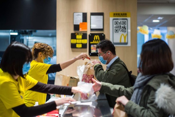 Members of staff (L) and customers (R) wear face masks at the counter of a MacDonald's fast food restaurant in Hong Kong on January 29, 2020, as a preventative measure following a coronavirus outbreak which began in the Chinese city of Wuhan. - The previously unknown virus has caused alarm because of its similarity to SARS (Severe Acute Respiratory Syndrome), which killed hundreds across mainland China and Hong Kong in 2002-2003. (Photo by Anthony WALLACE / AFP)