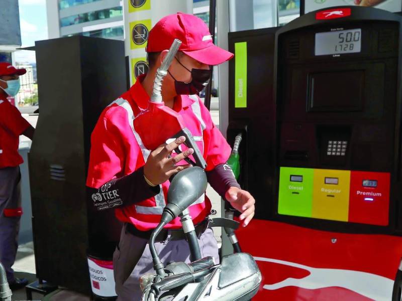 Empleado de una estación de servicio recargado combustible a una motocicleta.