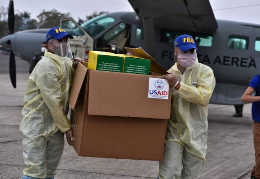 Miembros de las Fuerzas Armadas hondureñas llevan una caja que contiene parte de los 8,000 kits de pruebas de diagnóstico donados por la Agencia de los Estados Unidos para el Desarrollo Internacional (USAID) y la Organización Internacional para las Migraciones (OIM) a Honduras para combatir la pandemia del coronavirus COVID-19. AFP